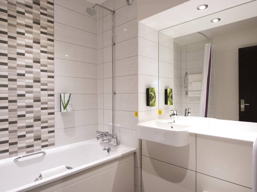 Un baño moderno con una bañera grande, dos lavamanos, ducha y un espejo.