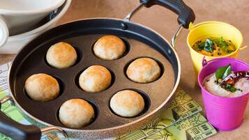 A cast iron skillet with six round items, possibly biscuits, on a colorful mat.