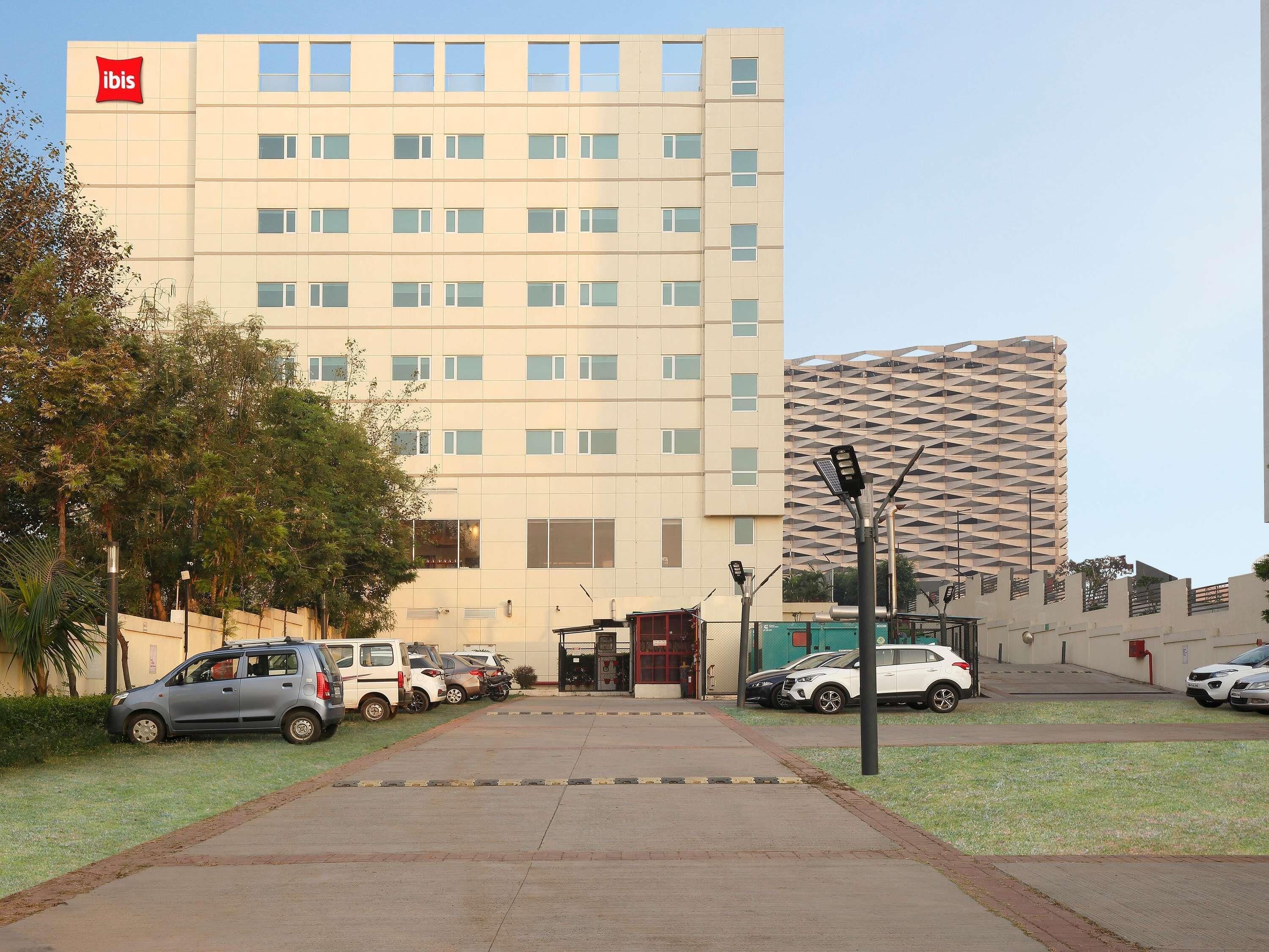 A hotel with a modern facade, multiple parking spaces, and a gated entrance.