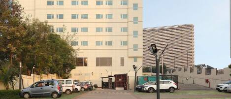 A hotel with a modern facade, multiple parking spaces, and a gated entrance.