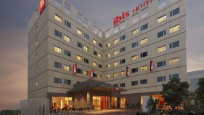 A modern hotel building with multiple floors, illuminated windows, and a prominent 'ibis Hotel' sign. - ibis Pune Hinjewadi Hotel (Paud)