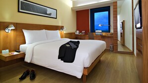 A hotel room with a bed, bedside tables, a desk with a laptop, a TV, and a large mirror. - ibis Pune Hinjewadi Hotel (Paud)
