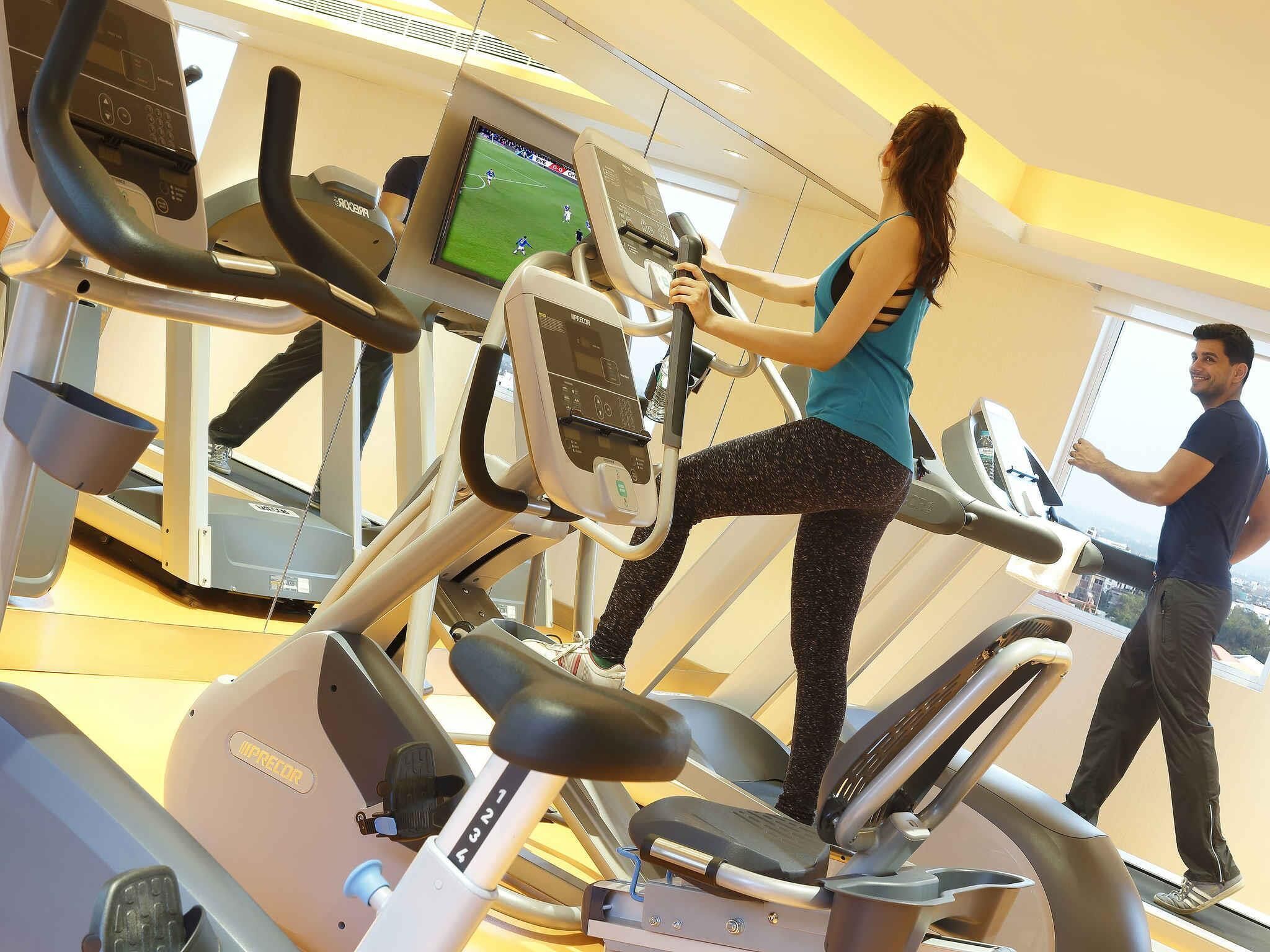 Une salle de sport avec des tapis de course, et un homme qui passe.
