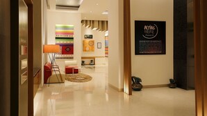 A hotel lobby with a reception desk, seating area, and a wall with motivational artwork. - ibis Pune Hinjewadi Hotel (Paud)