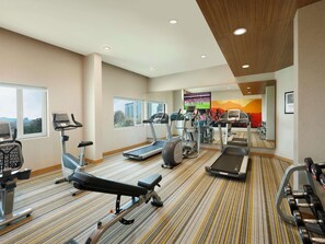 Un gimnasio con cintas de correr, elípticas y equipo de pesas.
