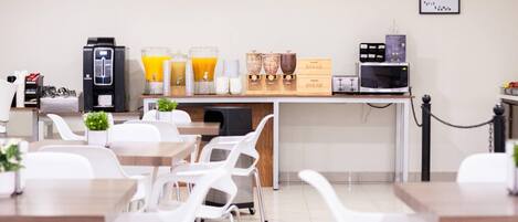 Un área de desayuno con cafetera, dispensadores de jugo y cajas para pan.