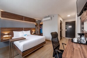 Une chambre d’hôtel moderne avec un lit en bois, une table de chevet et un bureau avec une chaise.
