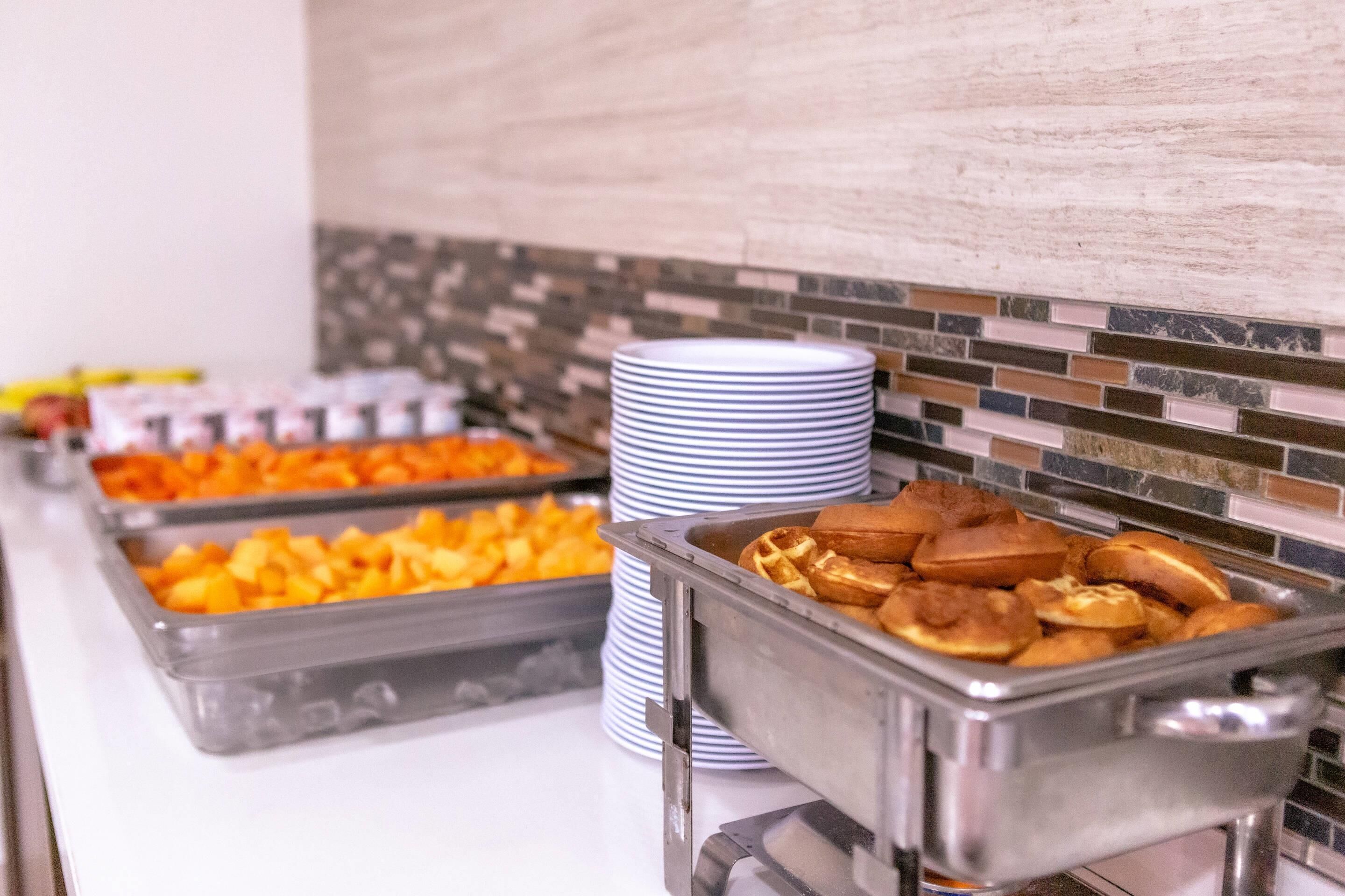 Un bufé con diversos alimentos y platos apilados.