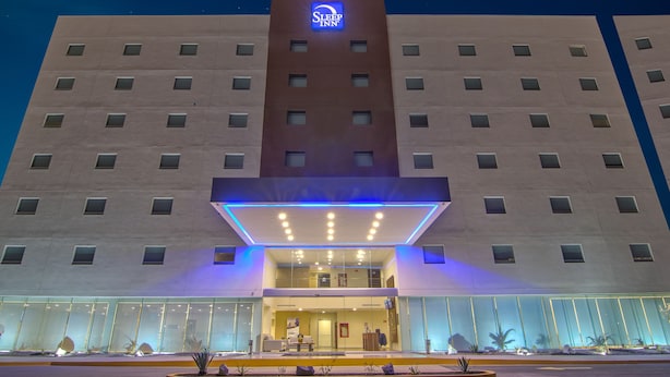 Ein Hotel mit einem gut sichtbaren Sleep Inn Schild, einer modernen Fassade und einem gut beleuchteten Eingang.
