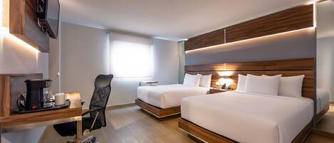 Habitación de hotel con dos camas, un escritorio con cafetera, una silla y un televisor montado en la pared.