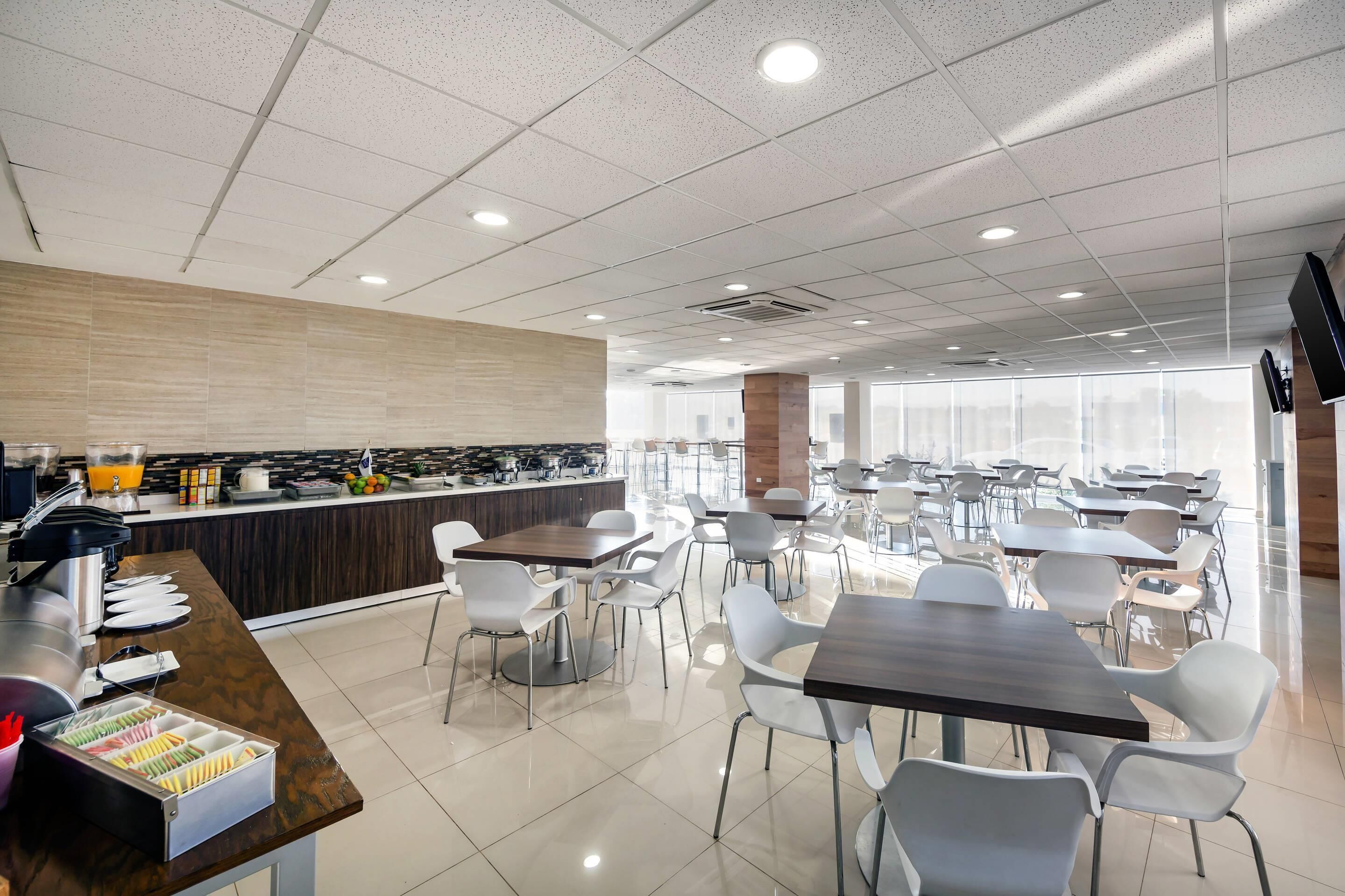 A modern cafeteria with a long counter, seating area, and large windows.
