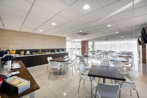 A modern cafeteria with a long counter, seating area, and large windows. - Sleep Inn Tijuana (Tijuana)