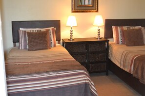 Two single beds with striped bedding, a nightstand between them, and a framed picture on the wall. - Kestell Hotel (Maluti a Phofung)