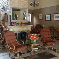 Una sala de estar acogedora con sillas de mimbre, chimenea y un espejo que refleja la habitación.