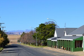 A street with buildings, a clear sky, and distant mountains. - Kestell Hotel (Maluti a Phofung)