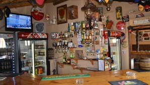 Eine Bar mit Regalen voller Flaschen, einem Fernseher und verschiedenen Dekorationen.