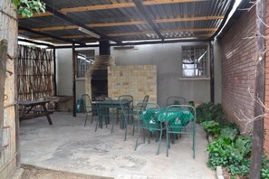 An outdoor patio with a stone fireplace, metal chairs, and a table. - Kestell Hotel (Maluti a Phofung)