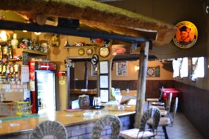 Una zona de bar con mostrador, sillas y varios objetos en estanterías.