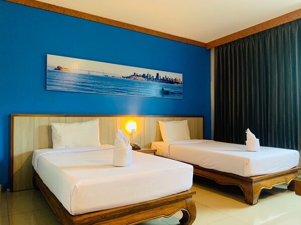 Habitación de hotel con dos camas, un cuadro de paisaje urbano y vista al mar.
