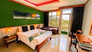 Habitación de hotel con una cama grande, un escritorio, una silla, un banco y vistas a zonas verdes.