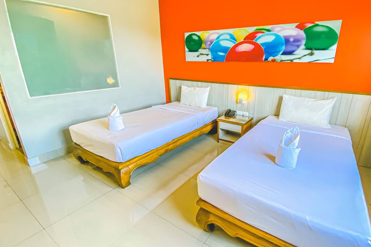 Een hotelkamer met twee bedden, een schilderij van ballonnen aan de muur, en een nachtkastje met een telefoon.