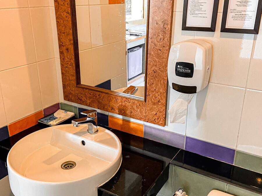 A bathroom with a white sink, a mirror, a soap dispenser, and a towel rack.