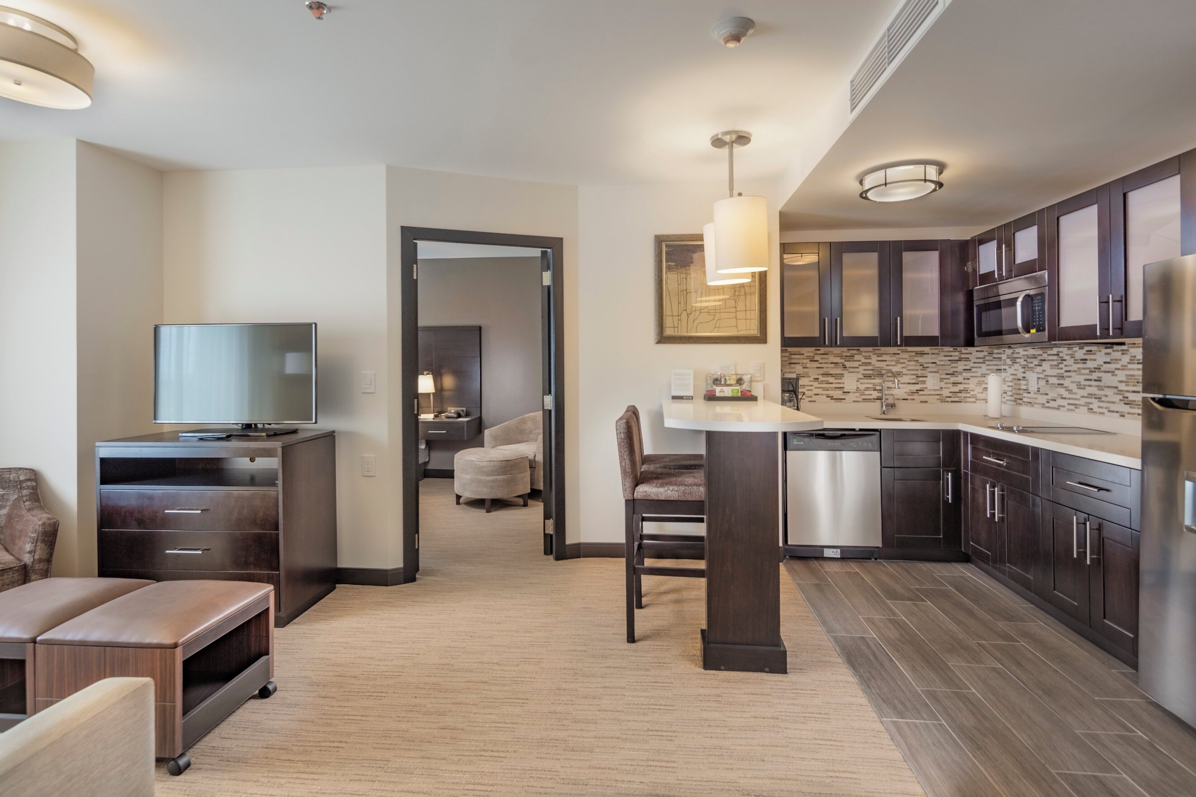 A modern kitchen with dark cabinetry, a stainless steel refrigerator, and a built-in dishwasher.