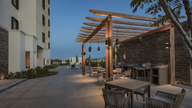 An outdoor patio area with a pergola, seating, and a grill station.