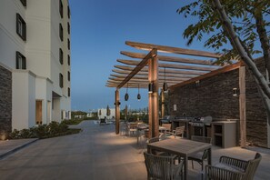 Un espacio al aire libre con patio, una pérgola, asientos y una estación de parrilla.