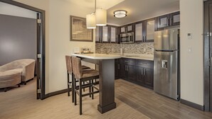 A modern kitchen with dark cabinets, stainless steel appliances, and a central island with chairs.