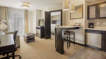 Una habitación de hotel moderna con comedor, kitchenette y un espejo grande.