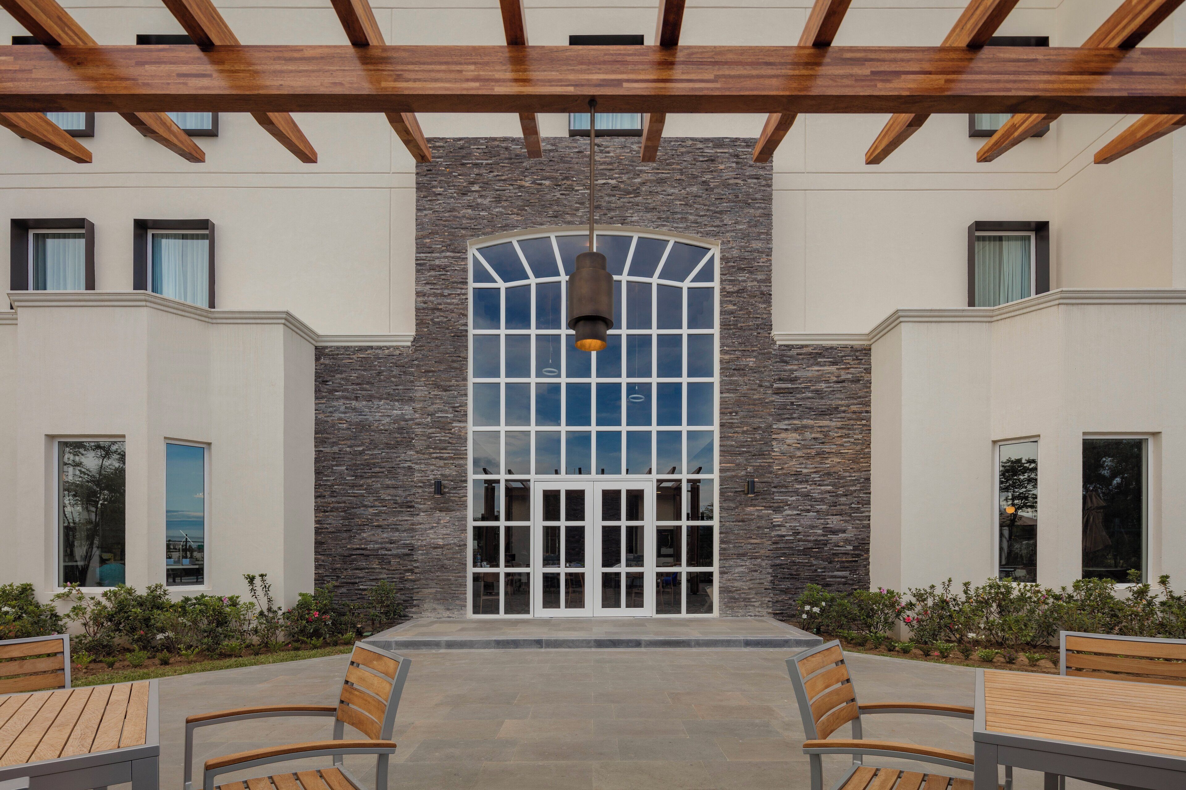 A building with a stone facade, large arched windows, and a covered outdoor seating area with benches.