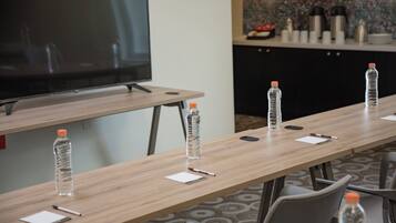 A conference room with a long table, chairs, a television, and water bottles.