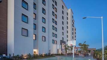 Un hotel de varios pisos con cancha de baloncesto y zona de estar al aire libre.