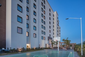 A multi-story hotel with a basketball court and outdoor seating area. - Staybridge Suites Silao by IHG (Silao)