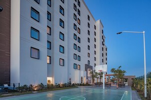 Un hotel de varios pisos con cancha de baloncesto y zona de estar al aire libre.