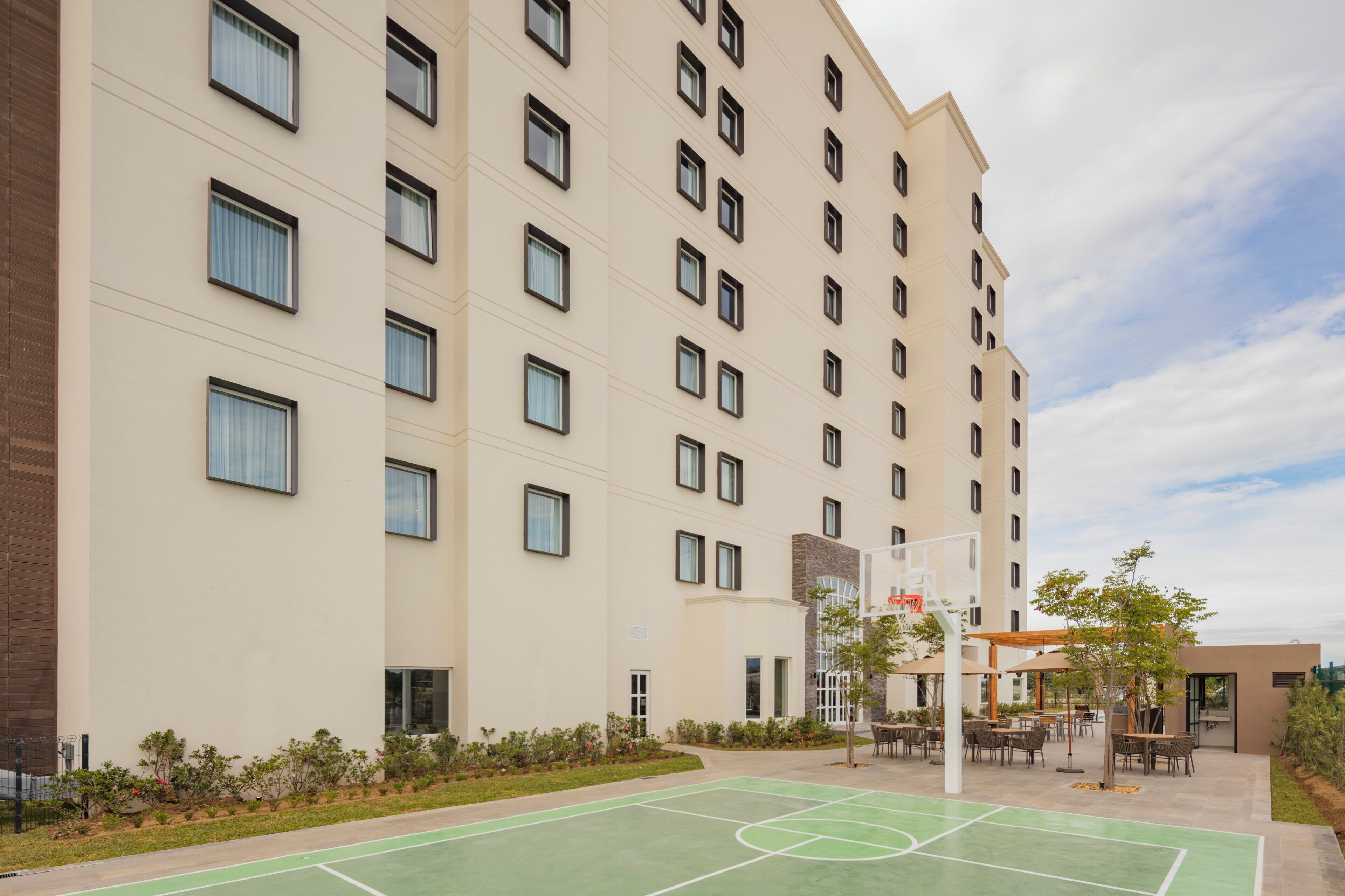 A multi-story hotel with a basketball court and outdoor seating area.