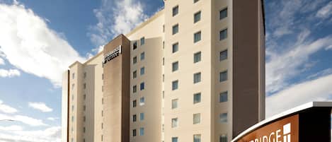 A Staybridge Suites hotel building with a modern design, multiple floors, and a clear sky in the background.