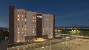 A multi-story hotel with a prominent 'Staybridge' sign, a parking lot, and a view of the cityscape in the background.
