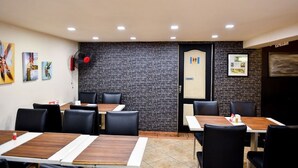 Un restaurante con pared de ladrillo, sillas de cuero negro y mesas de madera.