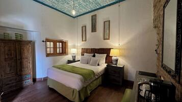 A bedroom with a wooden bed, bedside tables with lamps, a wardrobe, and a coffee maker on a side table.