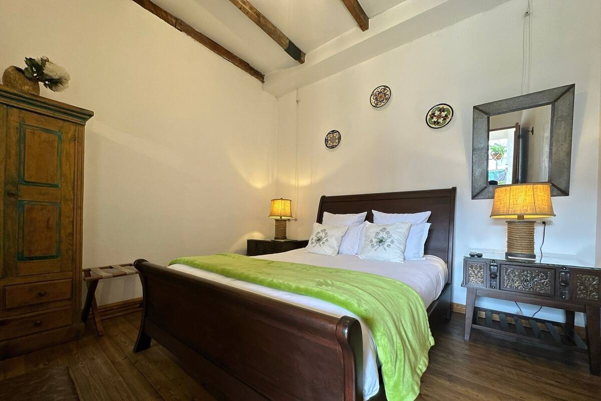 Une chambre à coucher avec un lit en bois, une commode et une table de chevet avec une lampe.