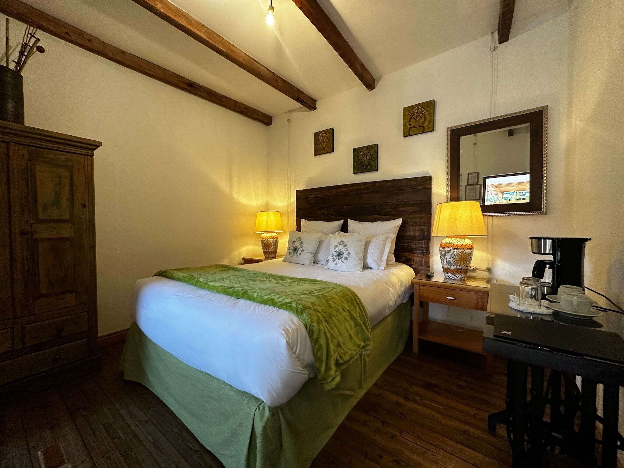 A bedroom with a wooden bed, bedside lamps, a dresser, and a coffee maker.