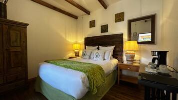 A bedroom with a wooden bed, bedside lamps, a dresser, and a coffee maker.