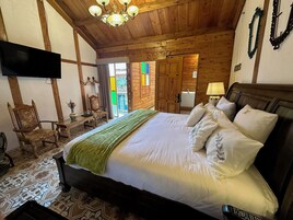 A wooden-paneled bedroom with a bed, a TV, a chair, and a table.