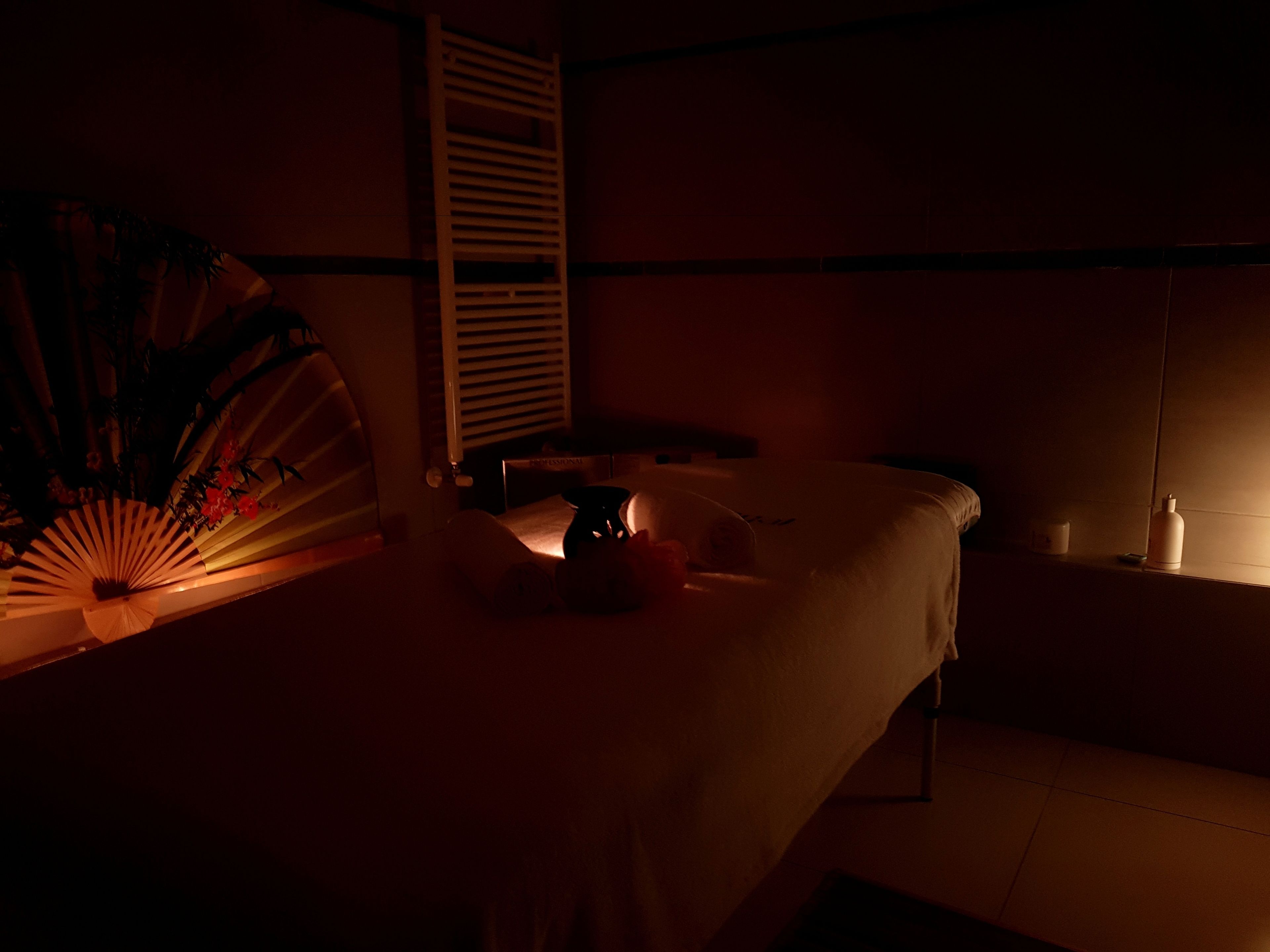 Ein schwach beleuchteter Raum mit einem Bett, einem Nachttisch und einem Wandregal.