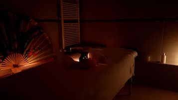 Ein schwach beleuchteter Raum mit einem Bett, einem Nachttisch und einem Wandregal.
