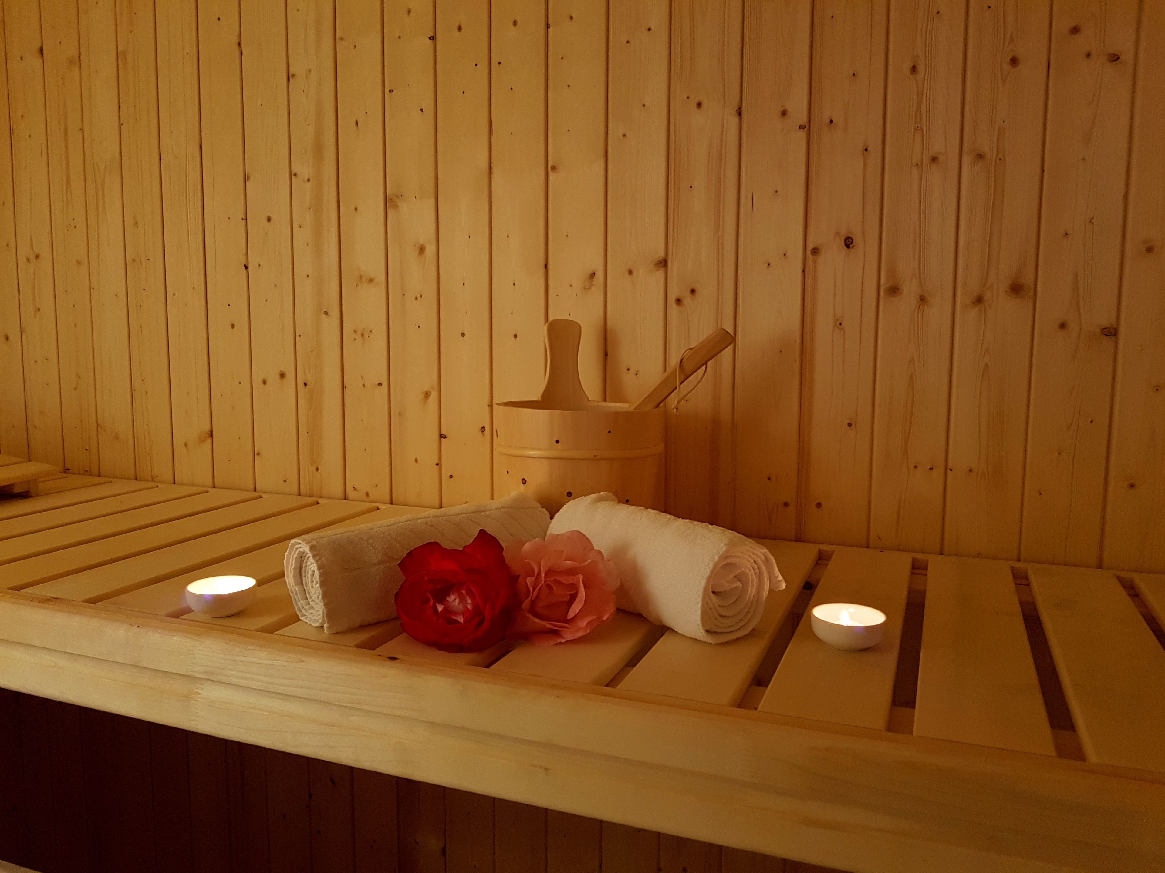 Banc de sauna de fusta amb tovalloles i una rosa vermella.