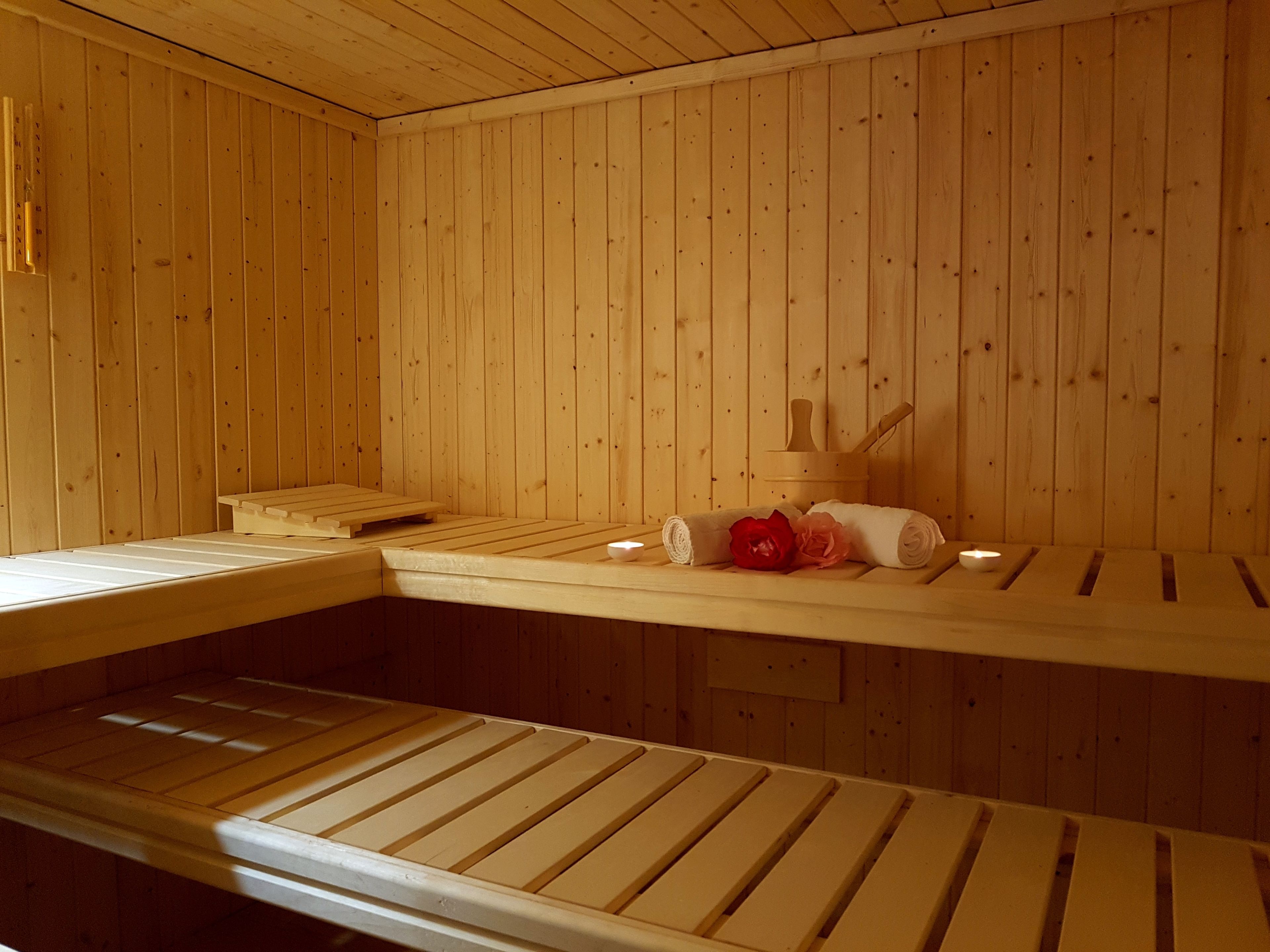 A wooden sauna with benches and a bench with a towel and a red rose on it.