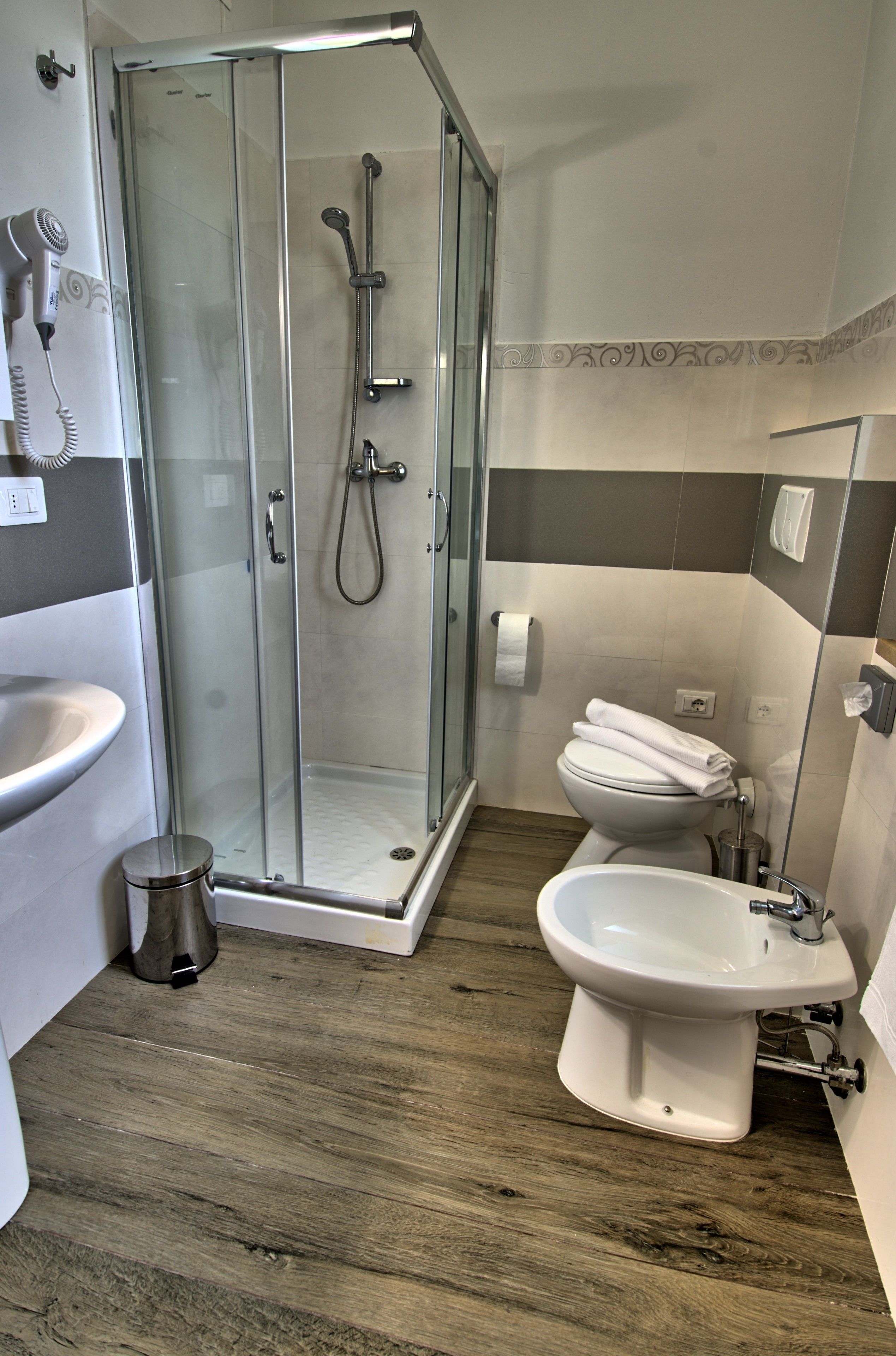 Ein Badezimmer mit einer Duschkabine, einem Waschbecken, einem Bidet und einer Toilette.